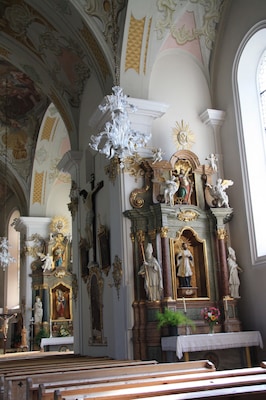 Italy, South Tyrol, Gossensaß. The church is dedicated to the Immaculate Conception and was built in 1750 on the same place of the old gothic church erected in 1471 and dedicated to Saint George of which remains the bell tower. The church was built on design of Franz de Paula Penz in baroque, it is possible a former project by Johann G. D. Grasmair. The church was consecrated on July 4 and 5, 1754 by bishop Leopold von Spaur. The front shows the portal of the old church and the three niches in which are placed the statues of the Immaculate Conception, Joachim and Saint Anne. The nave has a cross shape with two arms forming four lateral chapels. The high altar is rich in golden shades and at the centre of the throne is placed the statute of the Immaculate with the child was installed on April 23, 1752 by Josepf Stapf. The four statues are: St. George, St. Stephen, St. Lawrence and St. Florien. To the left side, between the two lateral chapels, is the baroque pulpit of 1777 positioned in a central site. To the right side between the two lateral chapels is a Crucifix by Bartlmä Kleinhans. The first right lateral altar is dedicated to Our Lady of Sorrows encircled by the statues of Mary Magdalene, Saint Elisabeth and Saint James works of 1750. The second right lateral altar is dedicated to Francis Xavier and two Bishops: Saint Ingenuinus and Saint Albuin coming from the old Saint George church. The first left lateral altar is the Flagellation of Christ at the column and the Saints Peter and John on each side. To the second left lateral altar is Saint Leonard, by side are the statues of Saint Sylvester, Saint Gregory and Saint Barbara coming from the old church. The eastern dome fresco was painted by Matthäus Günther and represents the Christ crowning Mary and Saint George throwing the pierced dragon downwards.