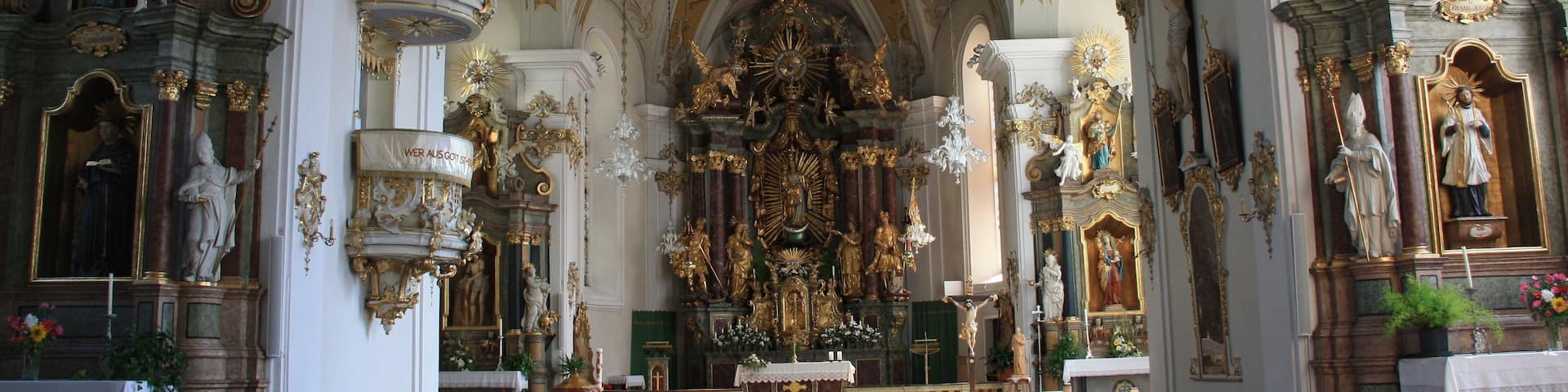 Italy, South Tyrol, Gossensaß. The church is dedicated to the Immaculate Conception and was built in 1750 on the same place of the old gothic church erected in 1471 and dedicated to Saint George of which remains the bell tower. The church was built on design of Franz de Paula Penz in baroque, it is possible a former project by Johann G. D. Grasmair. The church was consecrated on July 4 and 5, 1754 by bishop Leopold von Spaur. The front shows the portal of the old church and the three niches in which are placed the statues of the Immaculate Conception, Joachim and Saint Anne. The nave has a cross shape with two arms forming four lateral chapels. The high altar is rich in golden shades and at the centre of the throne is placed the statute of the Immaculate with the child. To the left side, between the two lateral chapels, is the baroque pulpit of 1777 positioned in a central site. To the right side between the two lateral chapels is a Crucifix by Bartlmä Kleinhans. The first right lateral altar is dedicated to Our Lady of Sorrows encircled by the statues of Mary Magdalene, Saint Elisabeth and Saint James works of 1750. The second right lateral altar is dedicated to Francis Xavier and two Bishops: Saint Ingenuinus and Saint Albuin coming from the old Saint George church. The first left lateral altar is the Flagellation of Christ at the column and the Saints Peter and John on each side. To the second left lateral altar is Saint Leonard, by side are the statues of Saint Sylvester, Saint Gregory and Saint Barbara coming from the old church. The eastern dome fresco was painted by Matthäus Günther and represents the Christ crowning Mary and Saint George throwing the pierced dragon downwards.