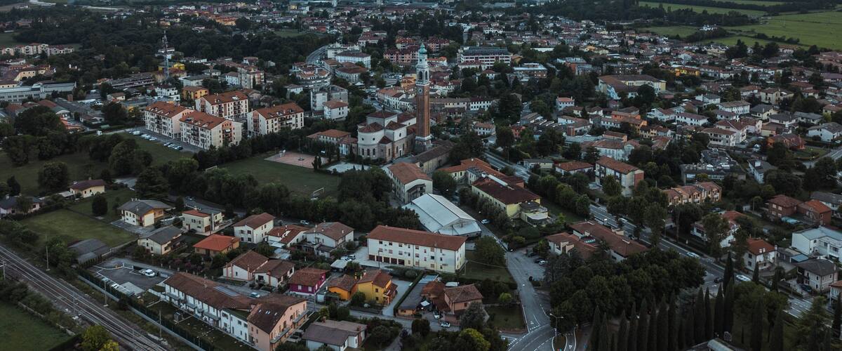 An aerial view of a town with a prominent church tower, residential buildings, and a railway line.