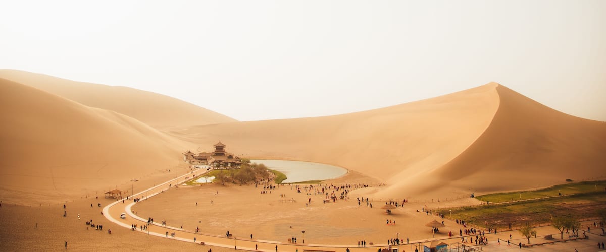 A desert landscape with sand dunes, a traditional pagoda, and a circular water feature.