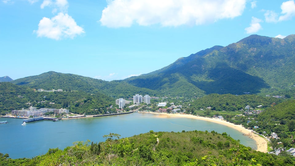A coastal landscape with a bay, a beach, and a mountain range.