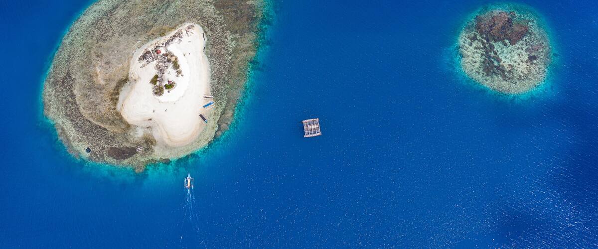 An aerial view of a large island with a white sandy beach and a smaller island nearby.