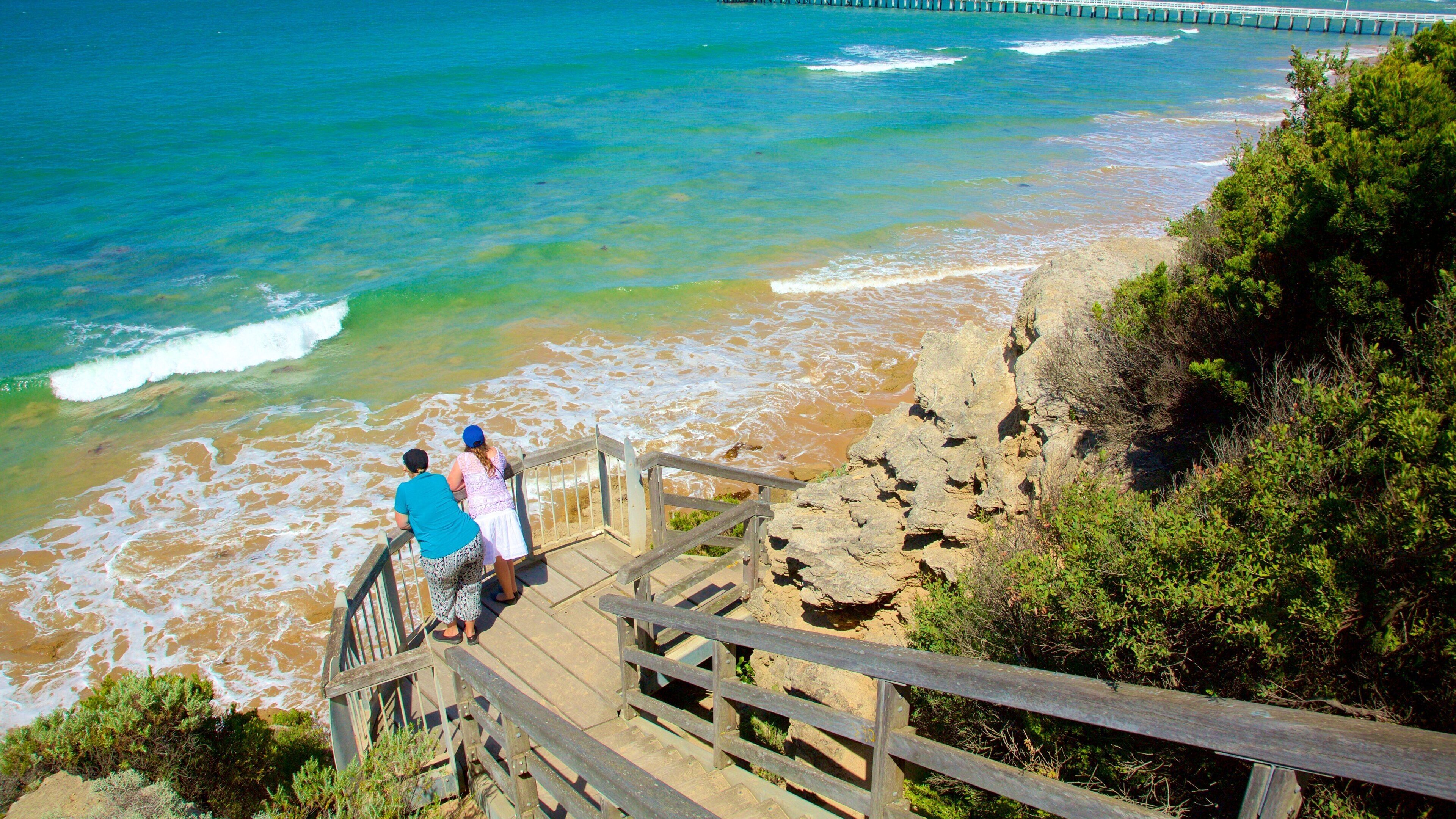 A wooden staircase leading to a beach with waves crashing onto the shore.