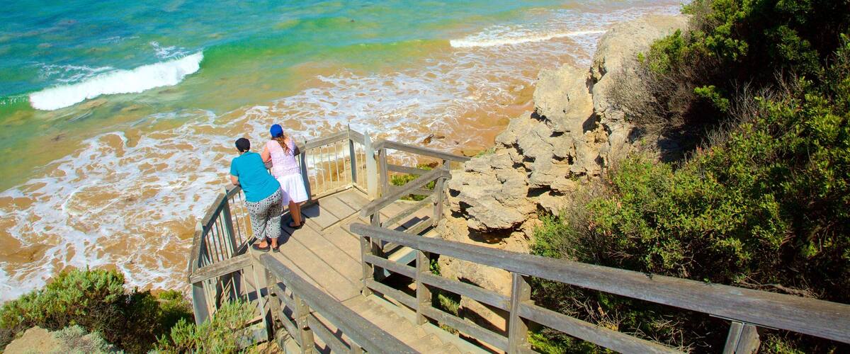 A wooden staircase leading to a beach with waves crashing onto the shore.