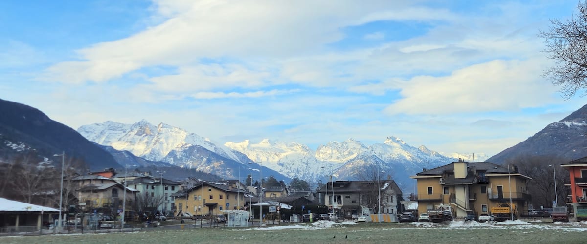 A town with buildings and snow-covered mountains in the background.