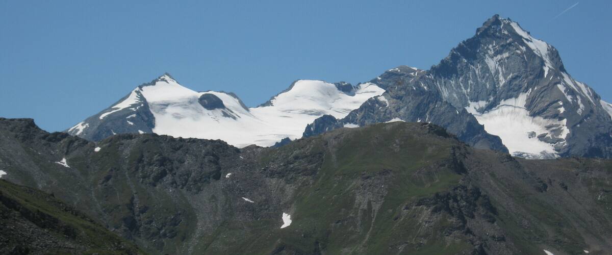 Une chaîne de montagnes aux sommets enneigés, sous un ciel bleu azur.