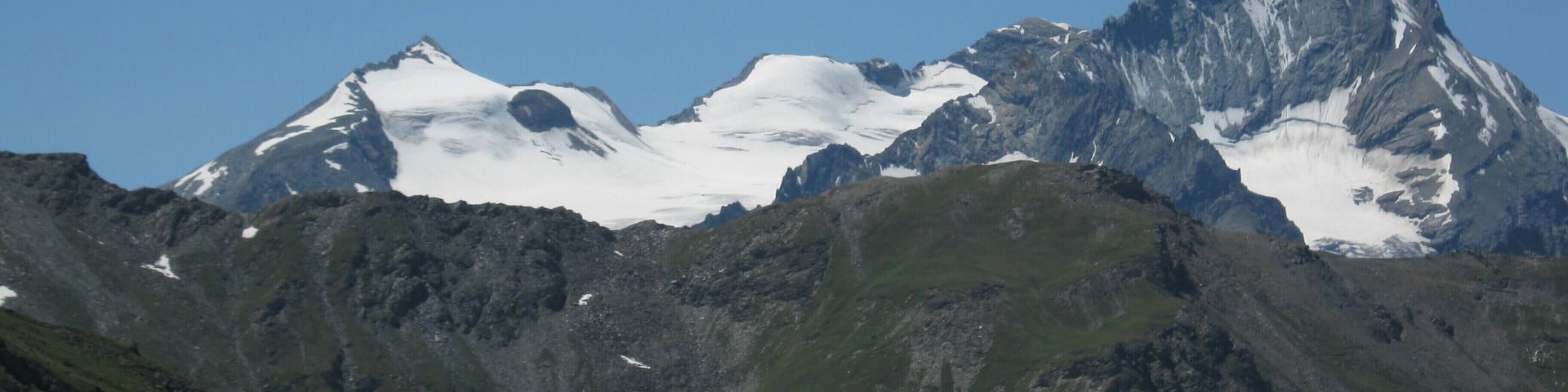 A mountain range with snow-capped peaks and a clear blue sky.