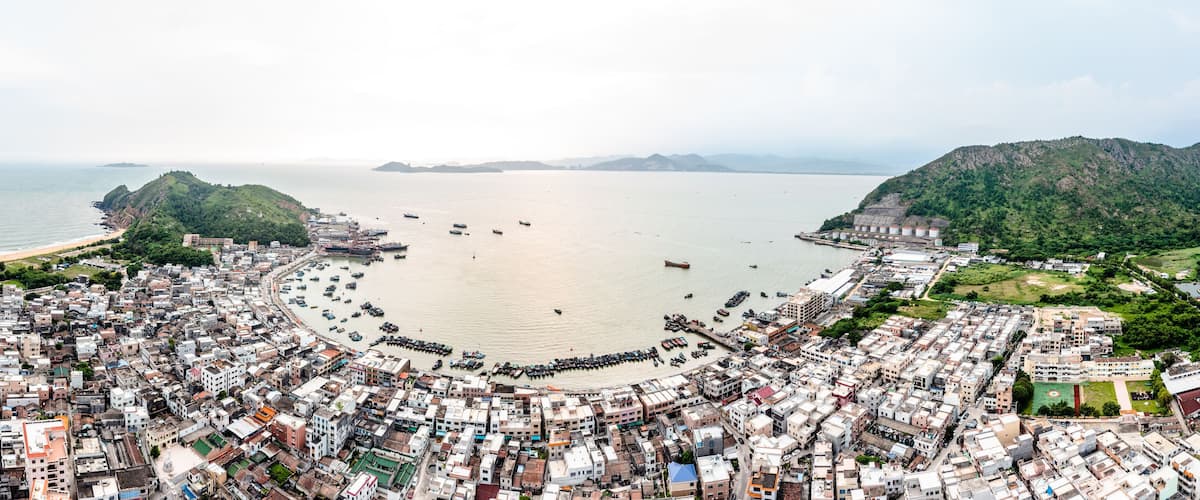 A coastal city with a densely packed urban area, a large bay, and surrounding hills.