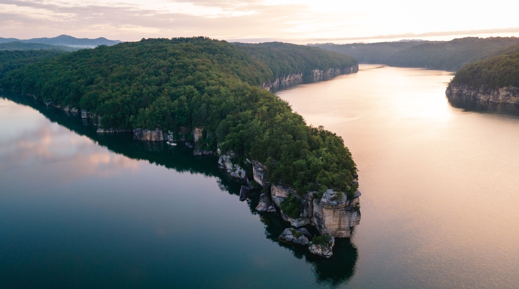 Une riviĂšre sinueuse traverse une pĂ©ninsule boisĂ©e, bordĂ©e dâune falaise dâun cĂŽtĂ© et dâun lac paisible qui reflĂšte le ciel de lâautre.