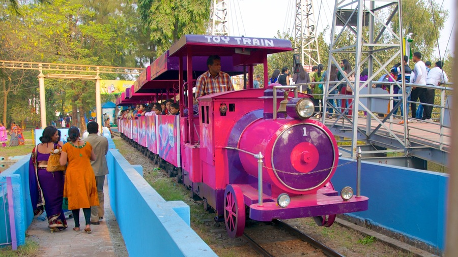 Un tren de juguete con una decoración morada y roja, pasajeros y una vía azul.