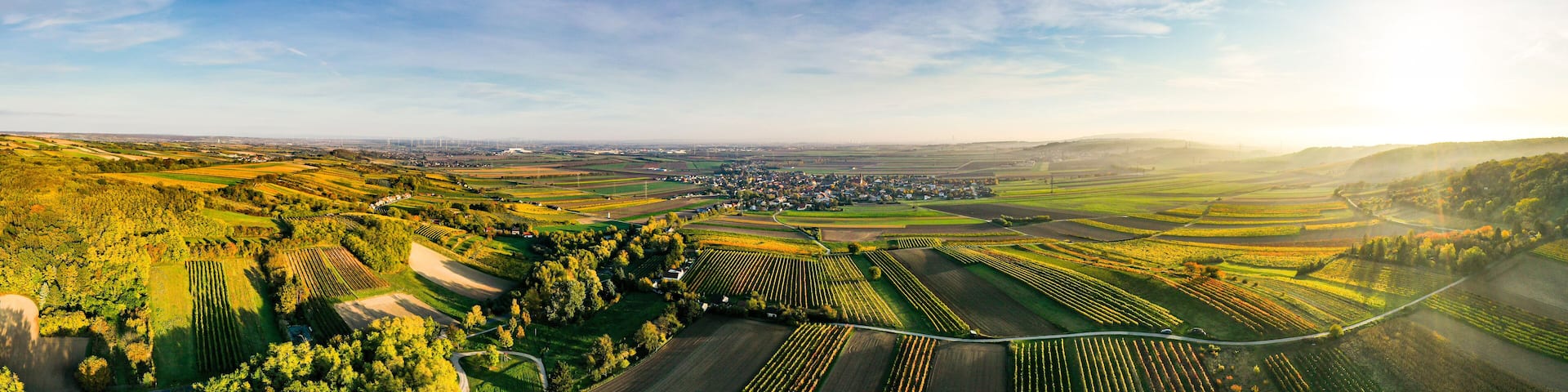 An aerial view of a rural landscape with fields, a small town, and rolling hills.