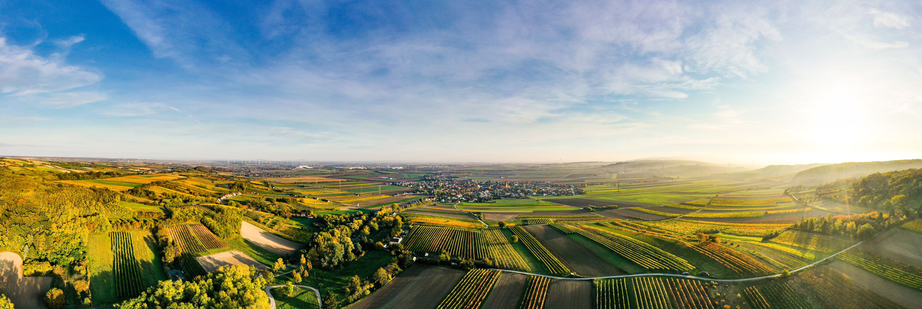 An aerial view of a rural landscape with fields, a small town, and rolling hills.