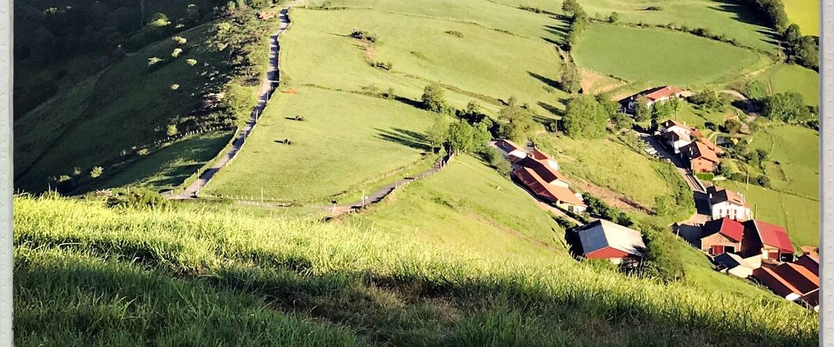A valley with rolling hills, a winding road, and scattered houses.