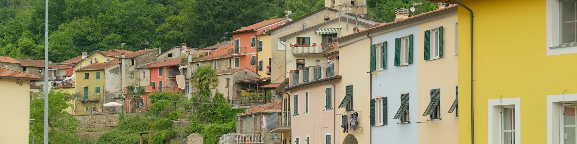 A hillside village with colorful buildings, a stone bridge, and a bell tower.
