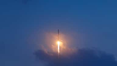 Rocket launch illuminating evening sky with glowing trail, aerospace program concept