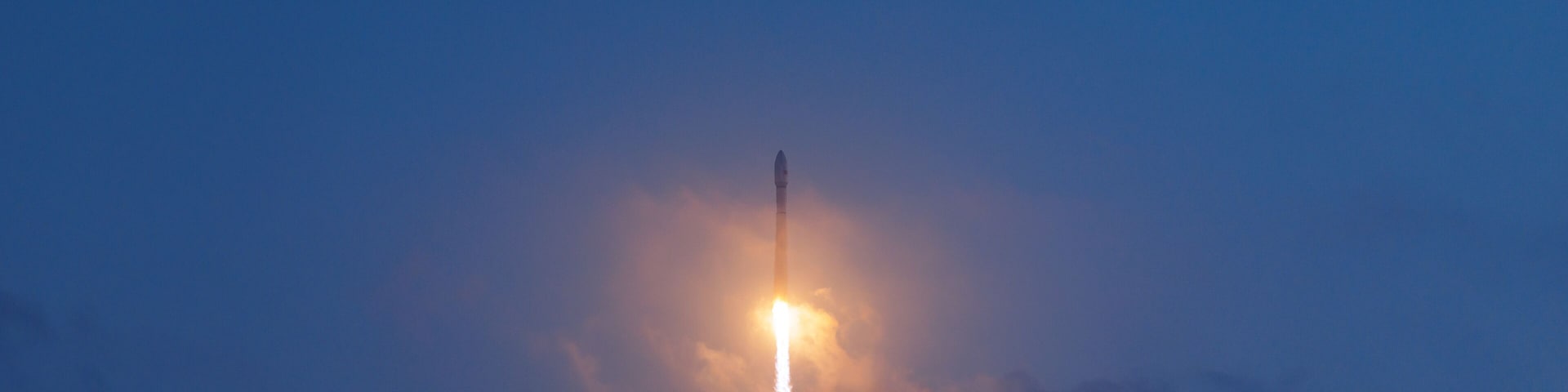 Rocket launch illuminating evening sky with glowing trail, aerospace program concept