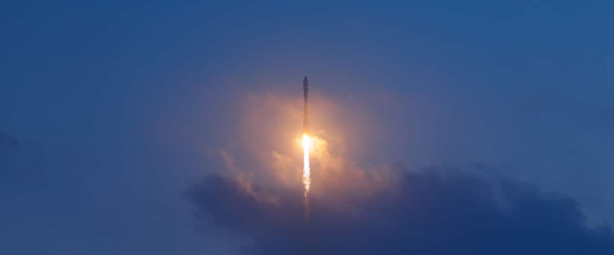 A rocket launch with a bright exhaust trail against a clear sky.