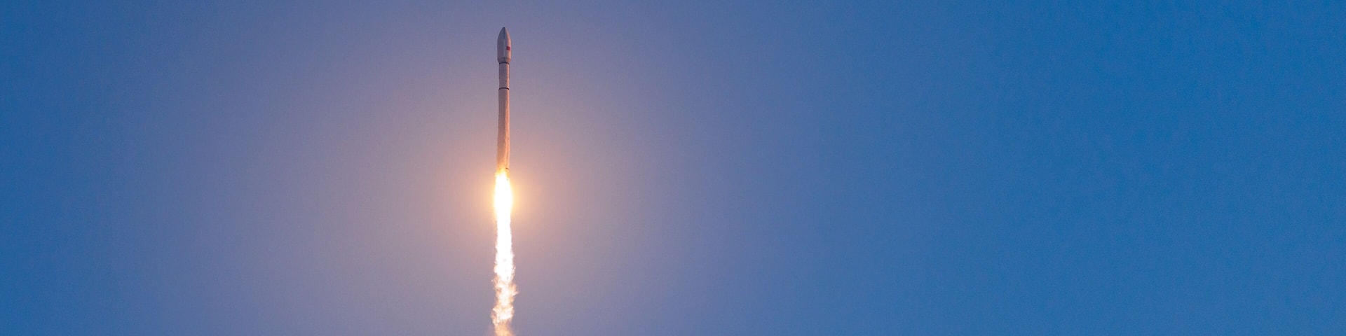 Rocket with satellites launch against clear blue sky at daytime, banner of concept aerospace program