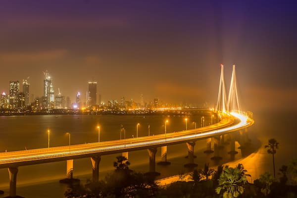 A nighttime cityscape with a prominent cable-stayed bridge and illuminated skyscrapers.