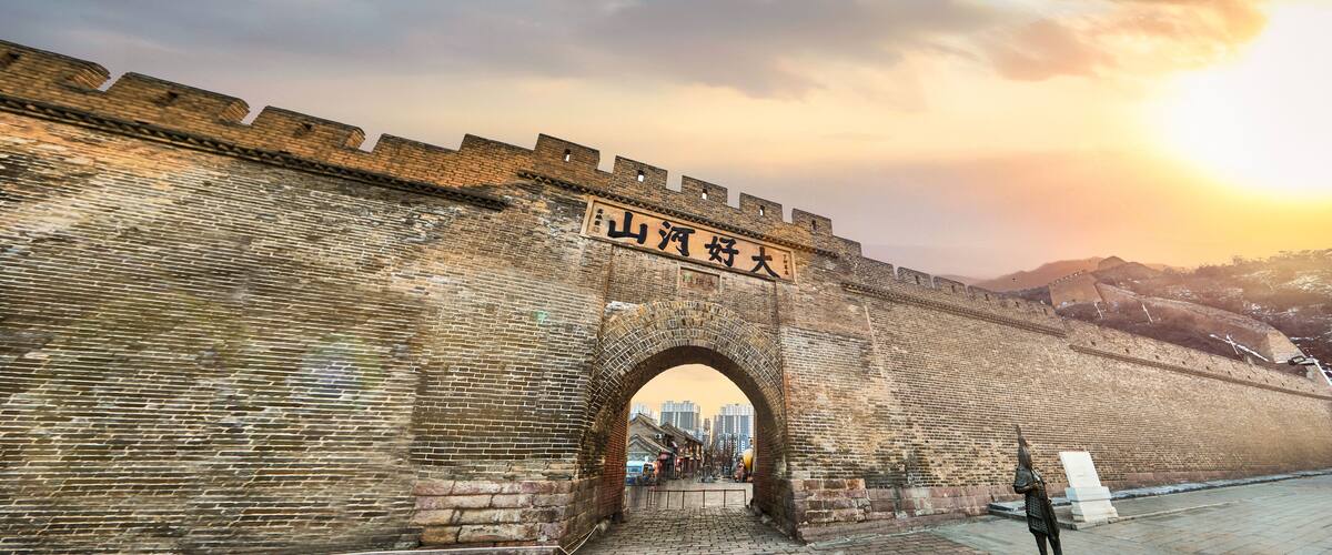 A large brick wall with a stone archway and a sign with Chinese characters.