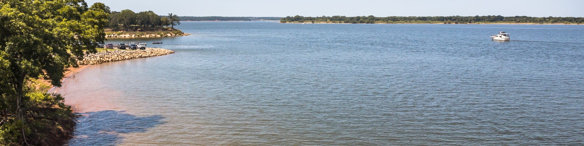 Un río tranquilo con un bote, una playa arenosa y una zona boscosa.