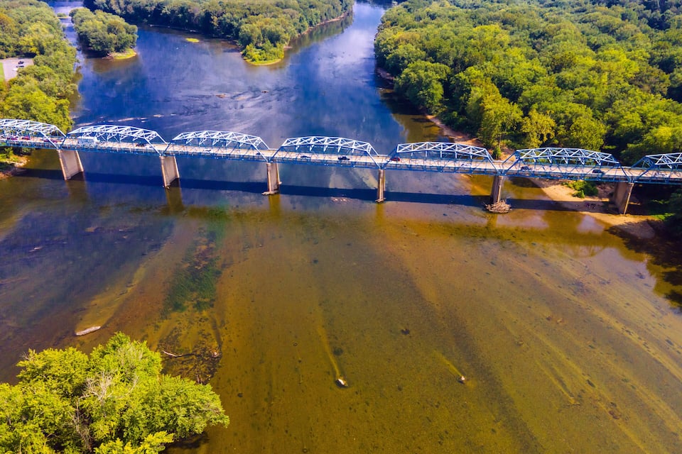 Een brug over een rivier, omringd door weelderige begroeiing.