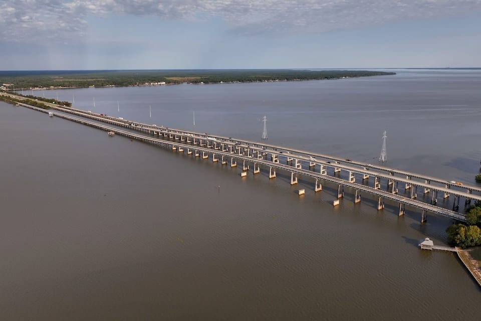A long bridge over a calm body of water with a clear sky.