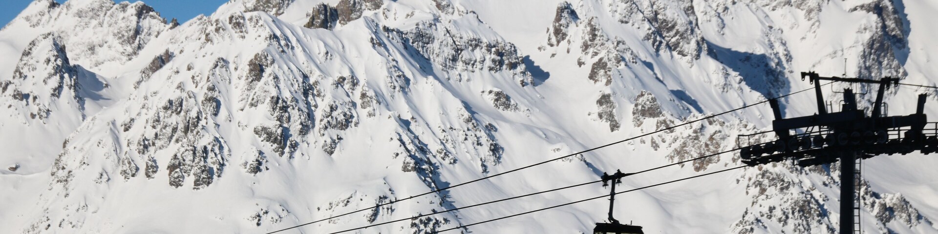 A snow-covered mountain with a cable car in the foreground.