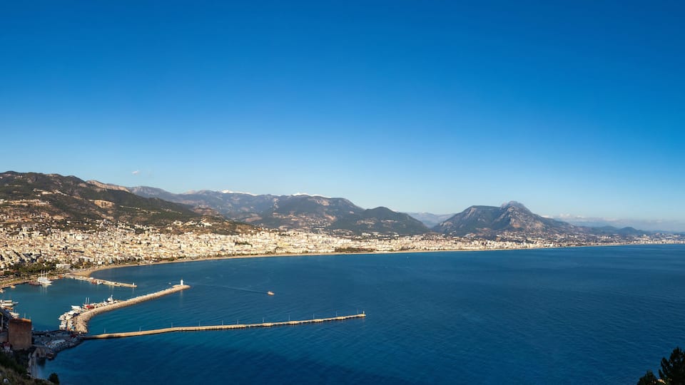 A coastal city with a bay, mountains, and a clear blue sky.