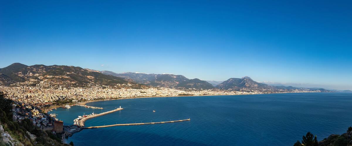 A coastal city with a bay, mountains, and a clear blue sky.