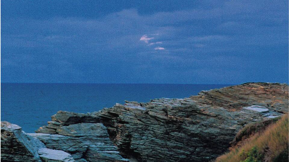 A coastal landscape with rocky cliffs and a visible rainbow.
