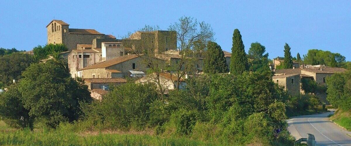 A rural landscape with a stone church, a road, and surrounding vegetation.