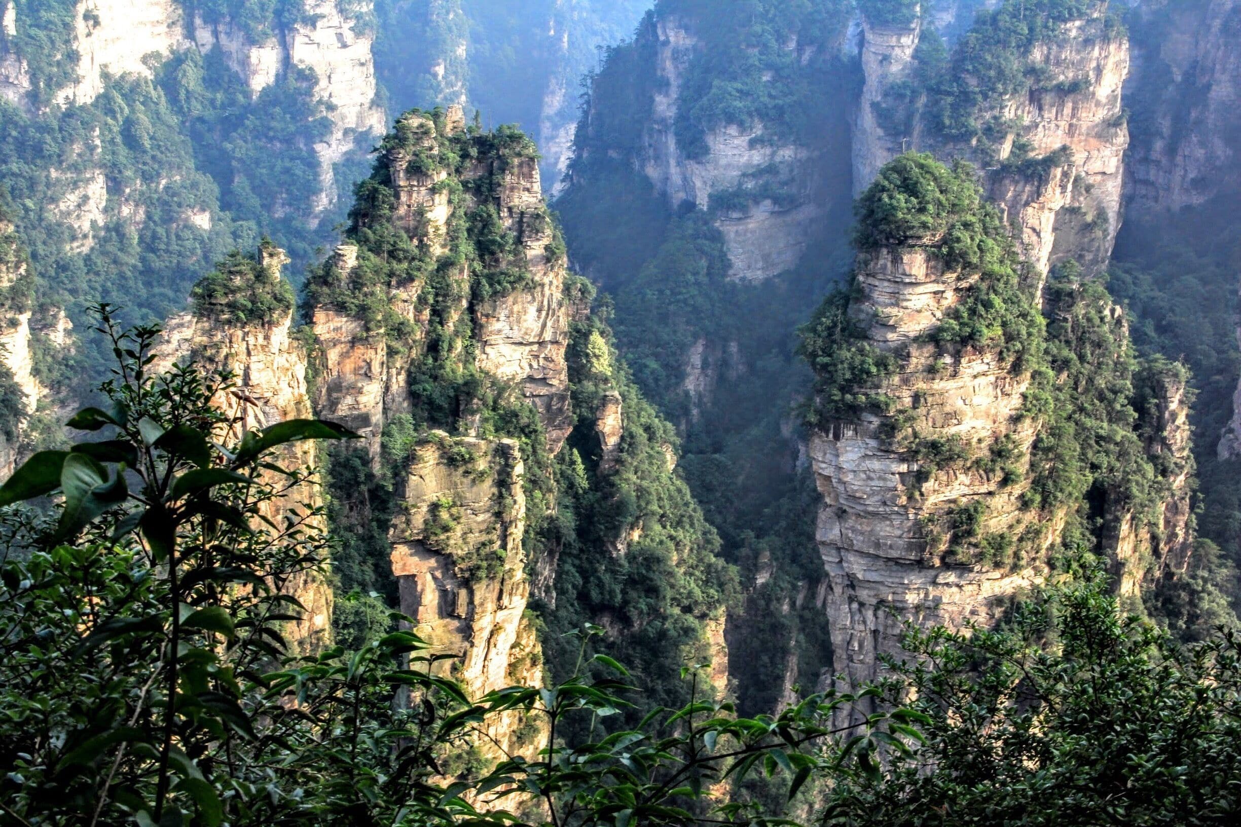 A mountainous landscape with towering cliffs and dense greenery.