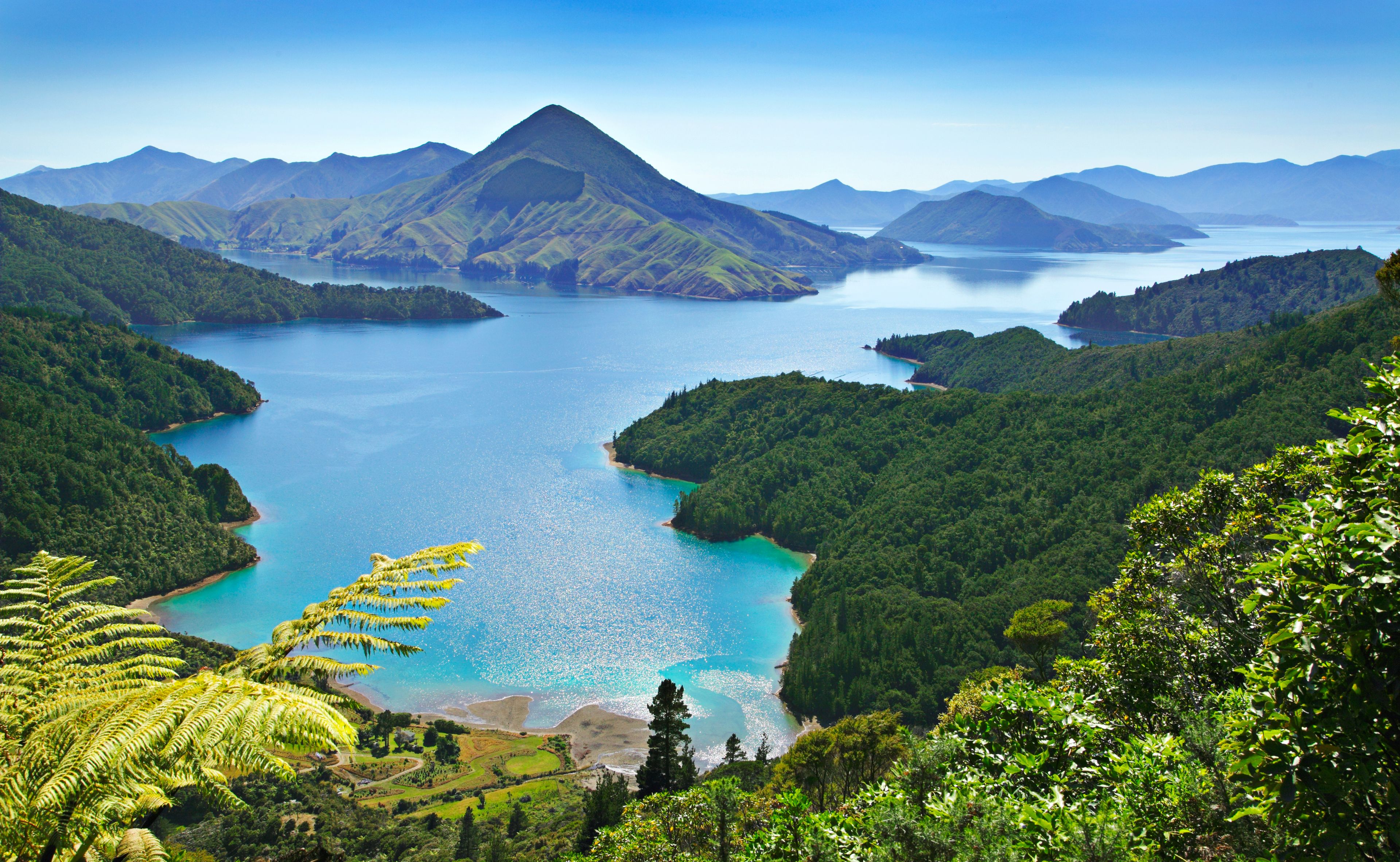 A coastal landscape with a large body of water surrounded by lush green hills and mountains.
