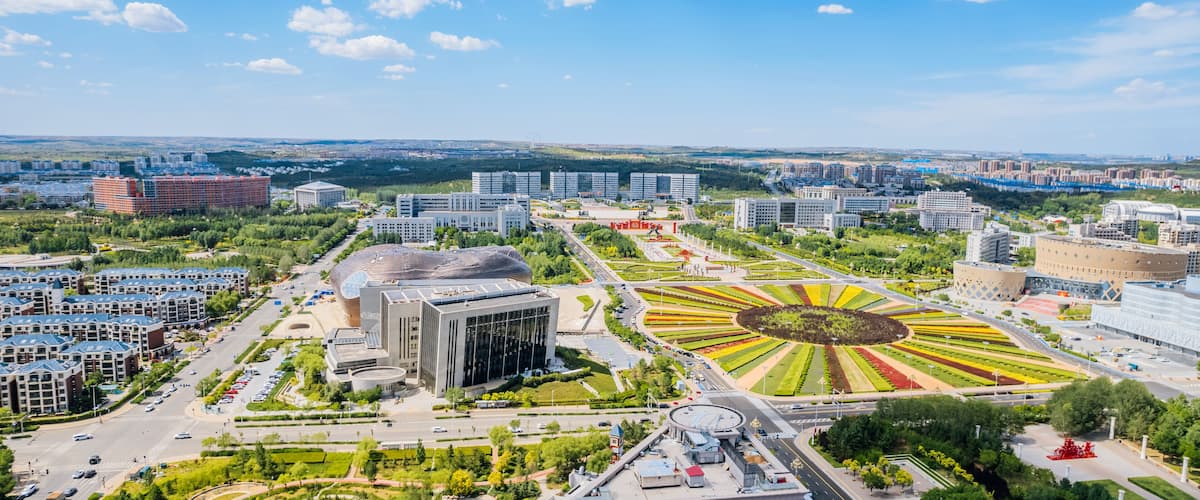 A cityscape with modern buildings, a large circular park, and a stadium.