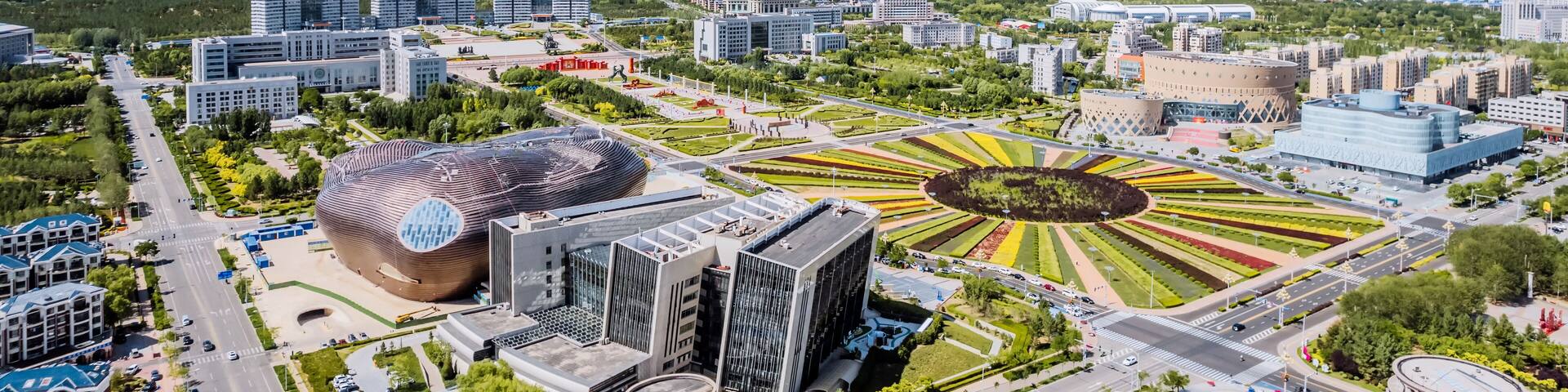 A cityscape with modern architecture, a distinctive circular park, and a large dome-shaped building.