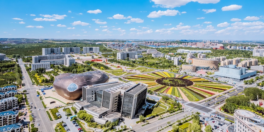 Un paisaje urbano con arquitectura moderna, un parque circular distintivo y un edificio grande con forma de cúpula.