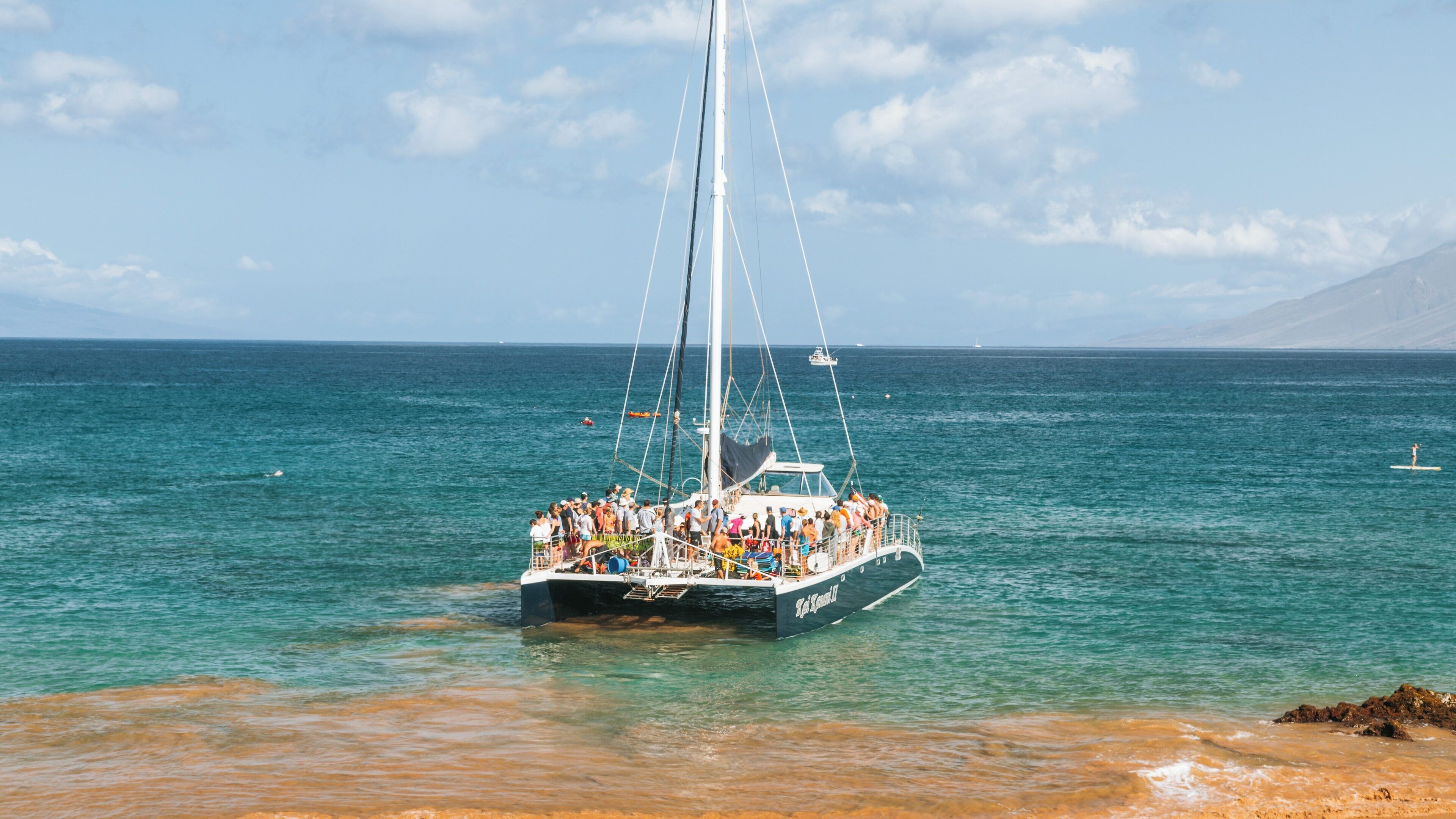 Charter boat anchored near Molokini Crater in Wailea, Hawaii with visitors enjoying the sunny day at sea