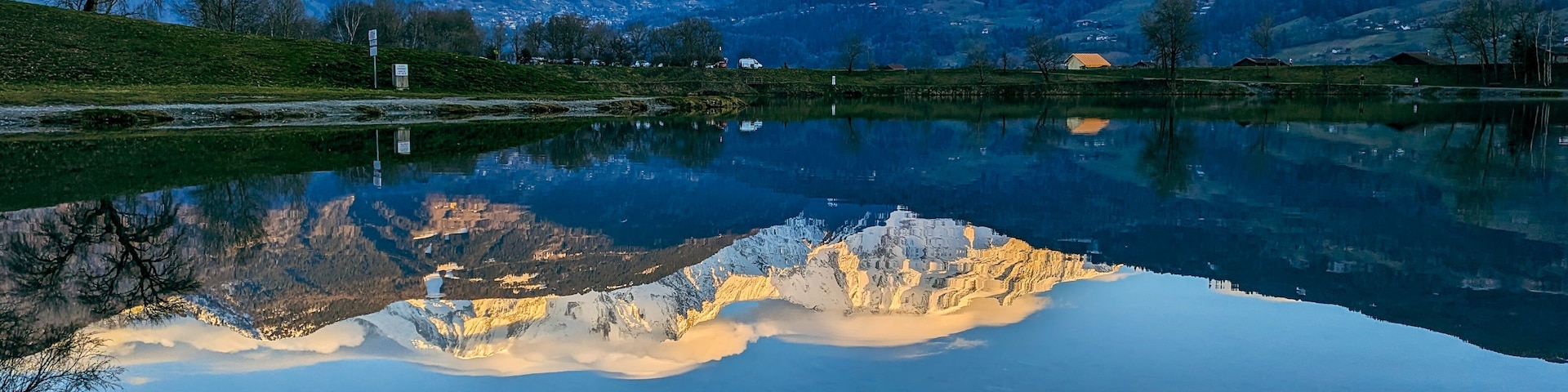 A mountain lake with reflections of the mountains and a clear sky.