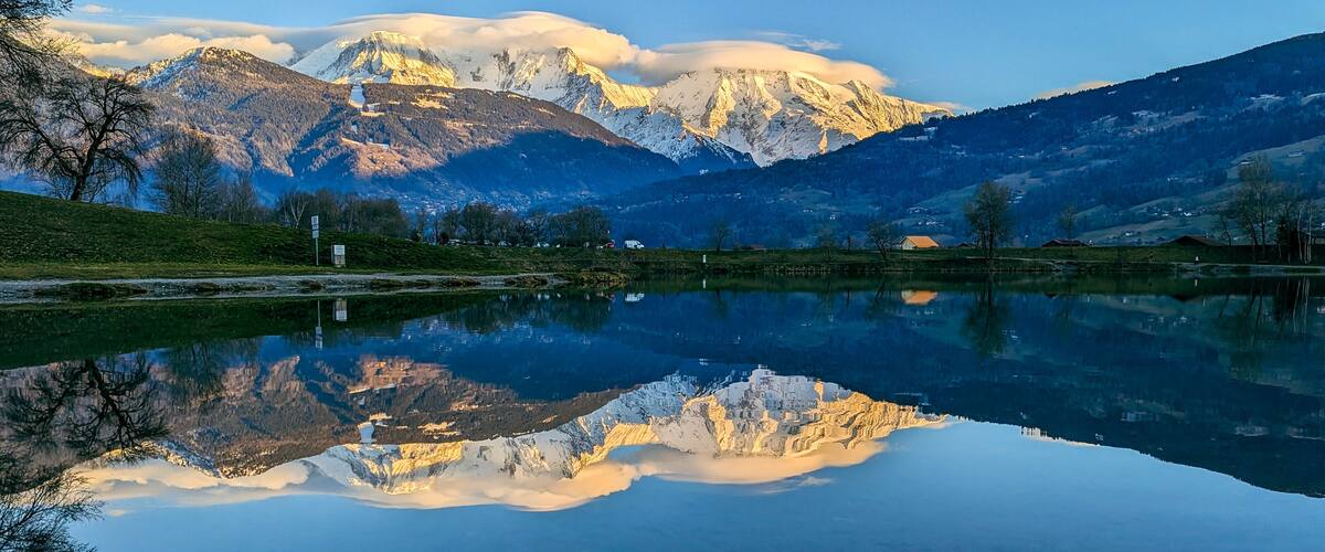 A mountain lake with reflections of the mountains and a clear sky.
