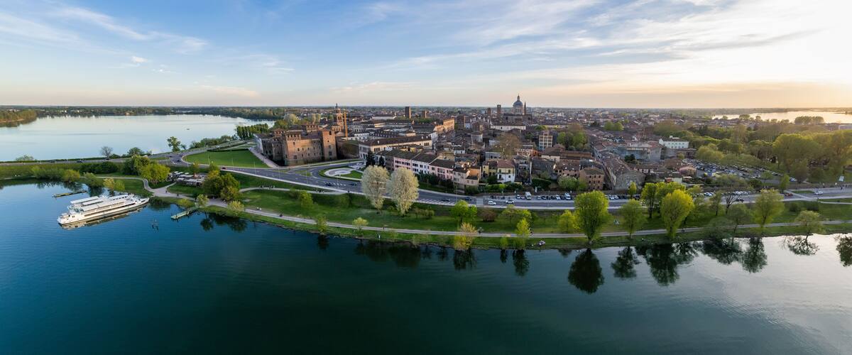 A riverside cityscape with historic buildings, a castle, and a cruise ship docked near the waterfront.