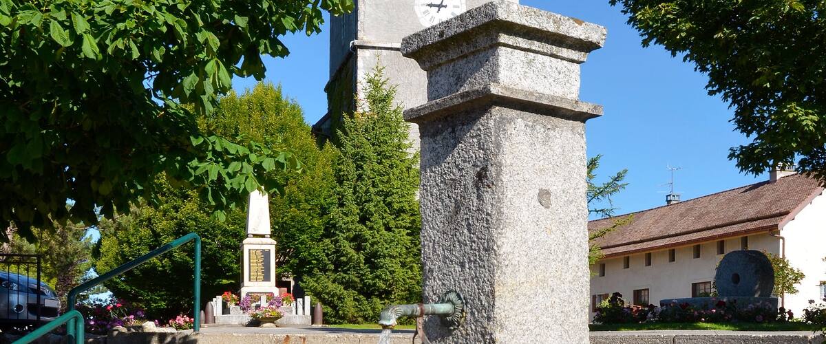 A stone fountain with a clock tower in the background.