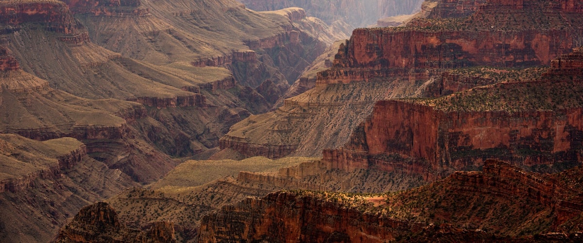 A canyon with layered rock formations and a river running through it.