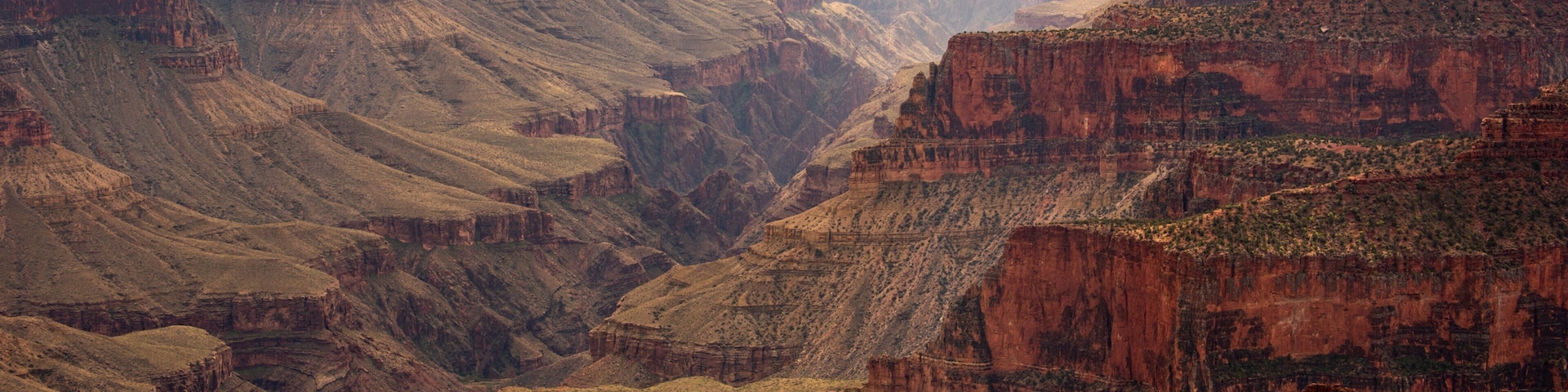 A canyon with layered rock formations and a river running through it.