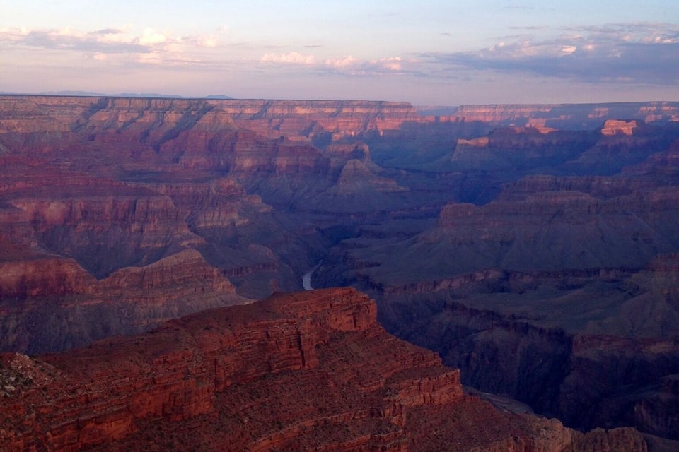 A canyon with layered rock formations and a river running through it.