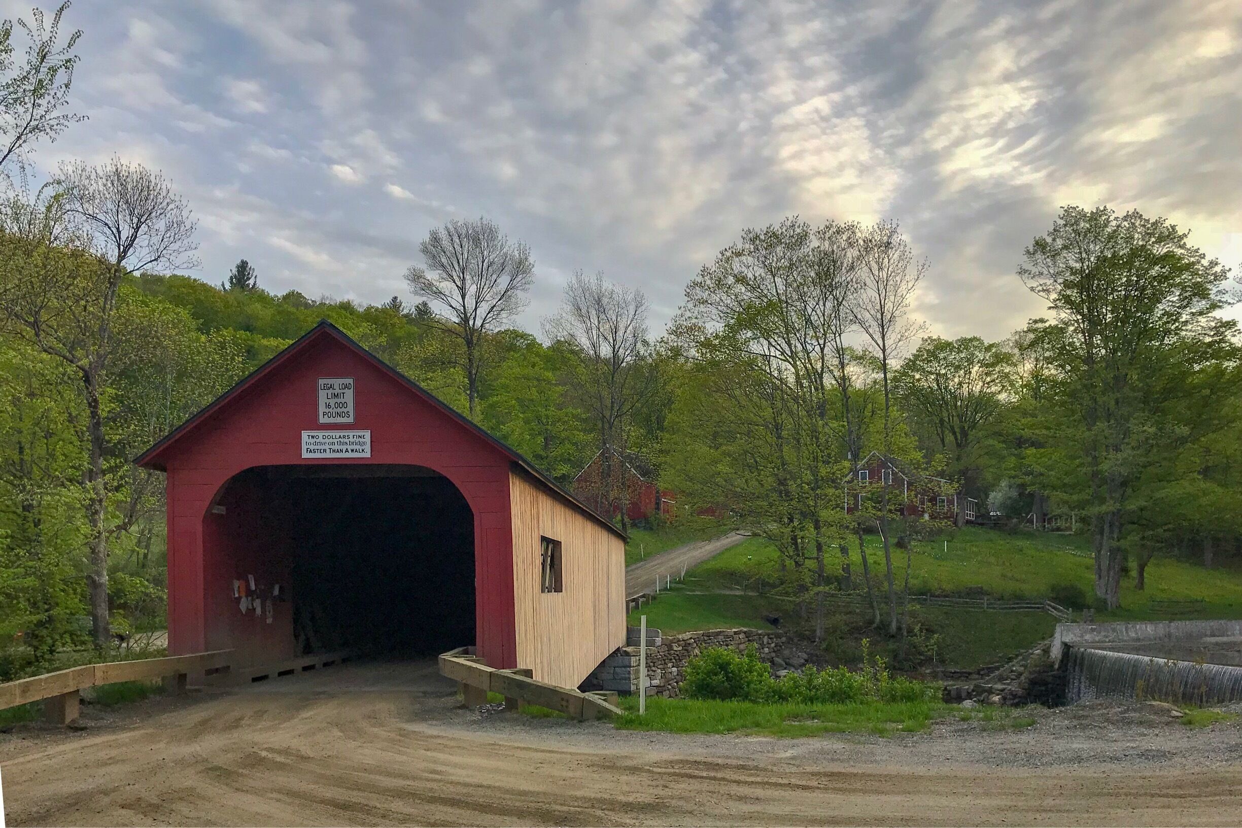 A red covered bridge with a sign indicating a legal load limit of 16,000 pounds.