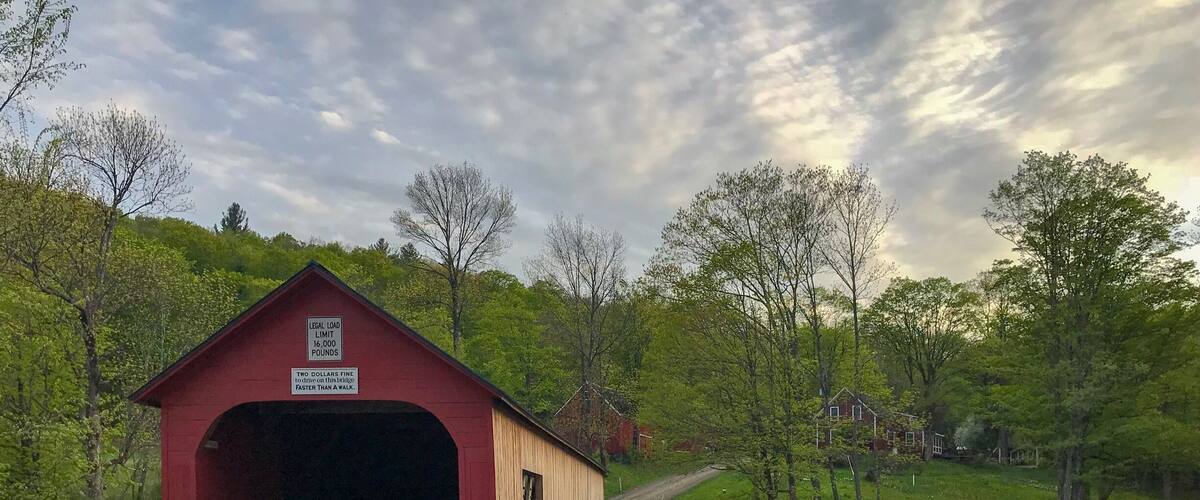 A red covered bridge with a sign indicating a legal load limit of 16,000 pounds.