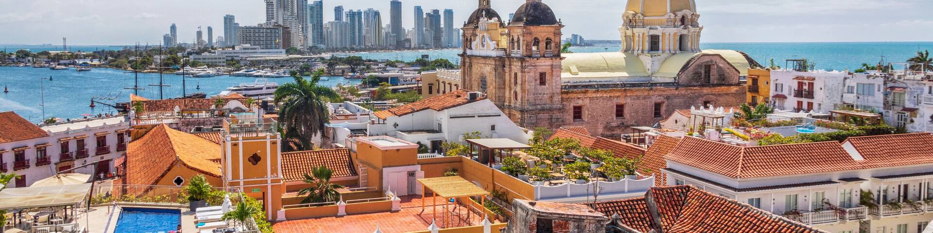 A coastal cityscape with historic buildings, a prominent church with a yellow dome, and a modern skyline in the background.
