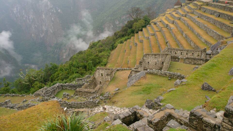 Ancient stone terraces and ruins in a mountainous landscape.