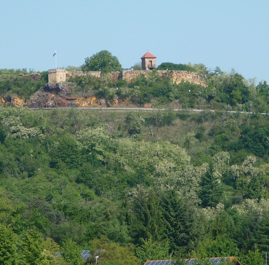 A hilltop with a stone tower and a flag.